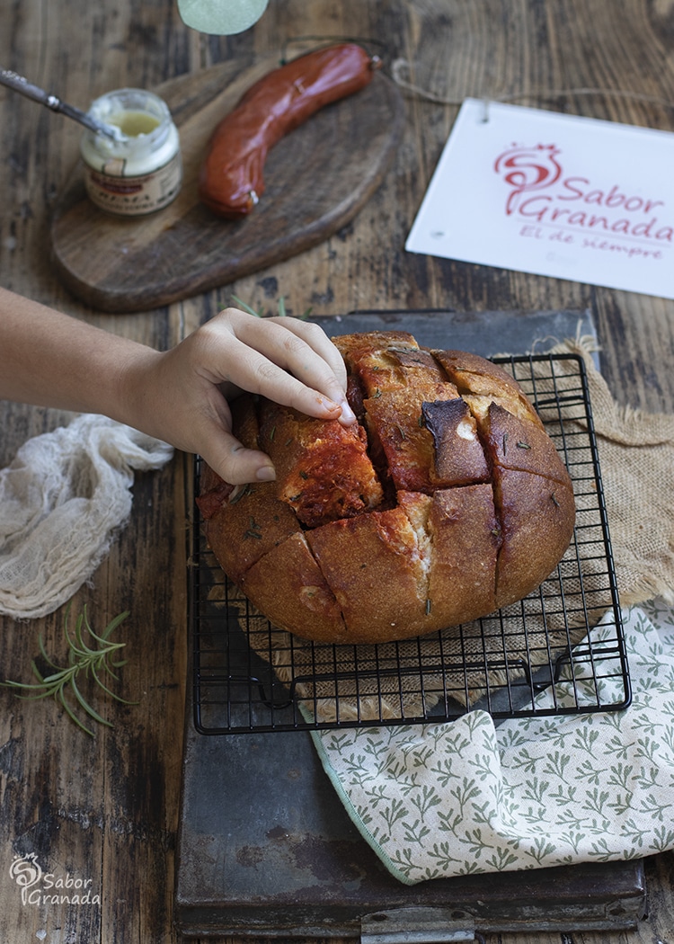 Cogiendo un trozo del pan al horno con crema de queso y sobrasada - Sabor Granada Cogiendo un trozo del pan al horno con crema de queso y sobrasada - Sabor Granada